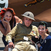 Elderly Veteran in his original World War II uniform flanked by two lovely ladies in '40s era clothing