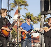photo of musicians with guitars singing and performing on an outdoor stage
