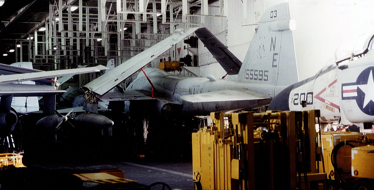 a6e-intruder-pcam-09 A-6E Intruder inside the hangar deck of an aircraft carrier, with wings folded and surrounded by equipment and other aircraft