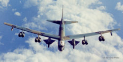 In-flight photo of a B-52 bomber with two D-21 drones, one under each wing. Photo is shot from above and in front of the bomber, with clouds below.