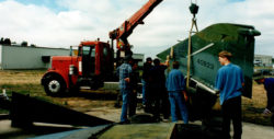 Old photograph of a crane truck unloading the parts of the F-4C Phantom II on the day the plane was delivered to the Pacific Coast Air Museum
