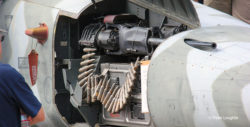 Close-up photo of the F-5E Tiger II gun compartment in the nose, showing a 20mm cannon and ammunition feed mechanism.