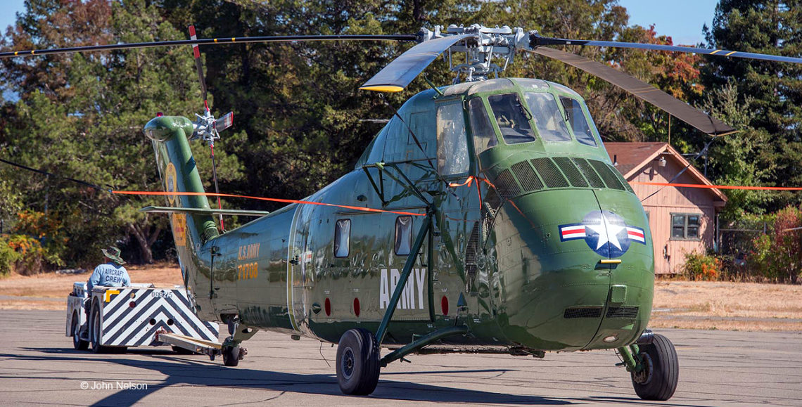 H-34 Choctaw helicopter being towed backward by a tow tractor.