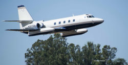 Lockheed Jetstar business jet making a low pass, with trees in the background.
