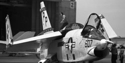 Black and White photo of an RF-86G Crusader on an aircraft carrier deck, with wingtips folded and canopy raised.