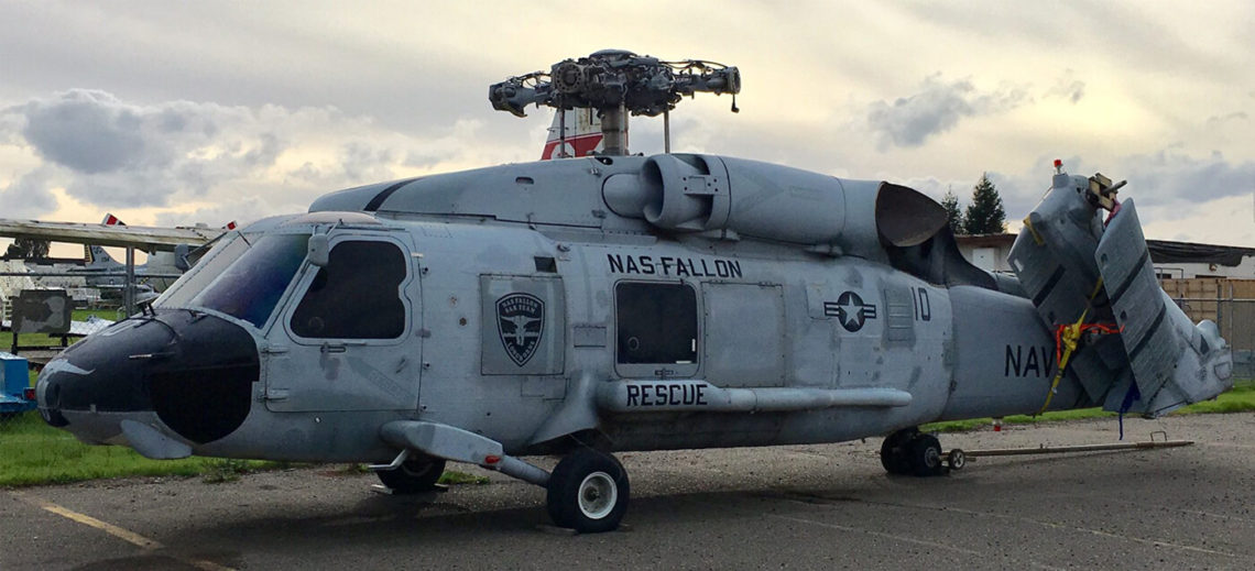 SH-60 Seahawk helicopter sitting on the ground with tail folded and no rotor blades