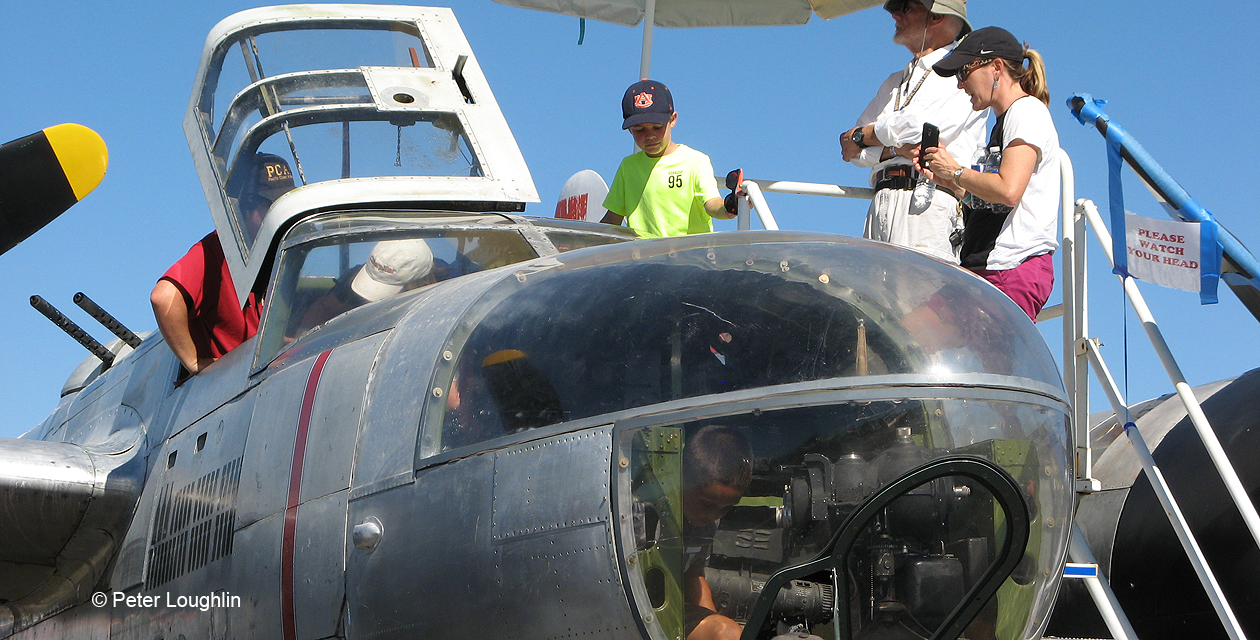 a26-invader-pcam-05 Close-up shot of A-26 Invader nose, from front right. Through the plexiglass windows you can see a young boy exploring the interior of the plane.