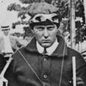 black and white photo of early aviator sitting in his airplane and looking very serious