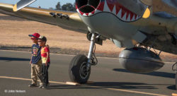 Two young children standing in front of a P-40 Warhawk for a photo