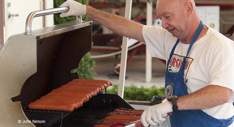 Man tending hot dogs on a gas grill