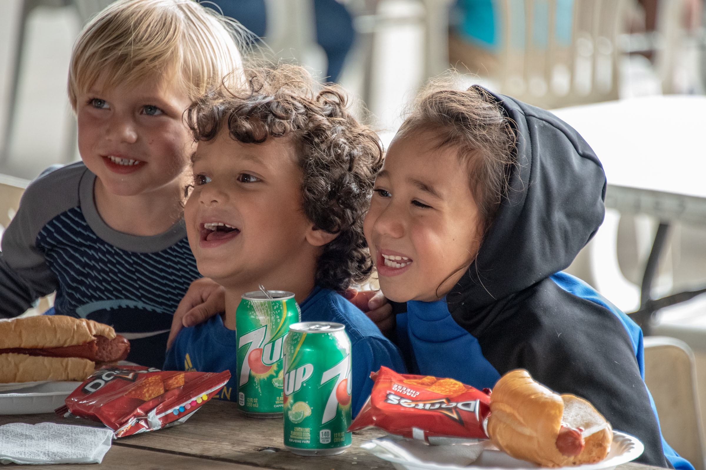 Kids smiling and eating hot dogs